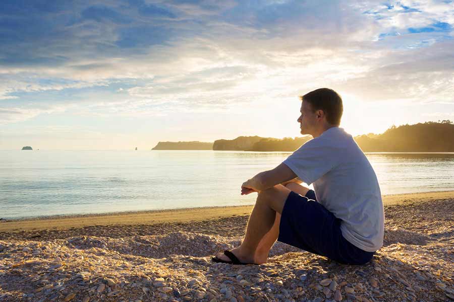 Guy sitting on the beach after his 12-step recovery program